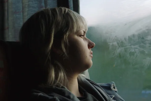 Loş bir otel koridorunda yürüyen genç bir kız
