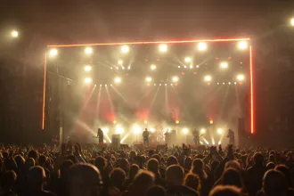 Gösterişli kostümler ve sahne ışıkları altında performans sergileyen rock grubu