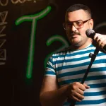 Sahnede spot ışığı altında performans sergileyen komedyen