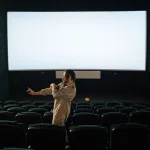 Teknoloji temalı karanlık bir sinema salonunda perdeye yansıyan görüntü