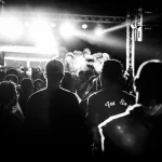 Pembe ışıklarla aydınlatılan bir konser sahnesi ve kalabalık
