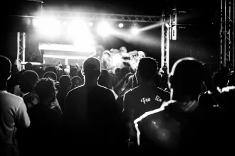 Pembe ışıklarla aydınlatılan bir konser sahnesi ve kalabalık