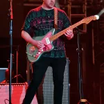 Sahnede gitar çalan bir müzisyenin görüntüsü