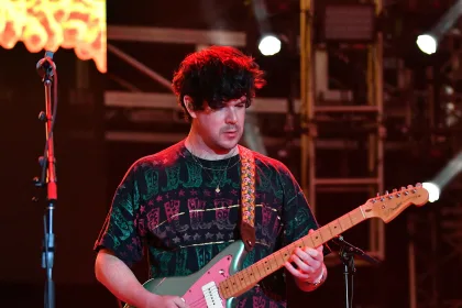 Sahnede gitar çalan bir müzisyenin görüntüsü