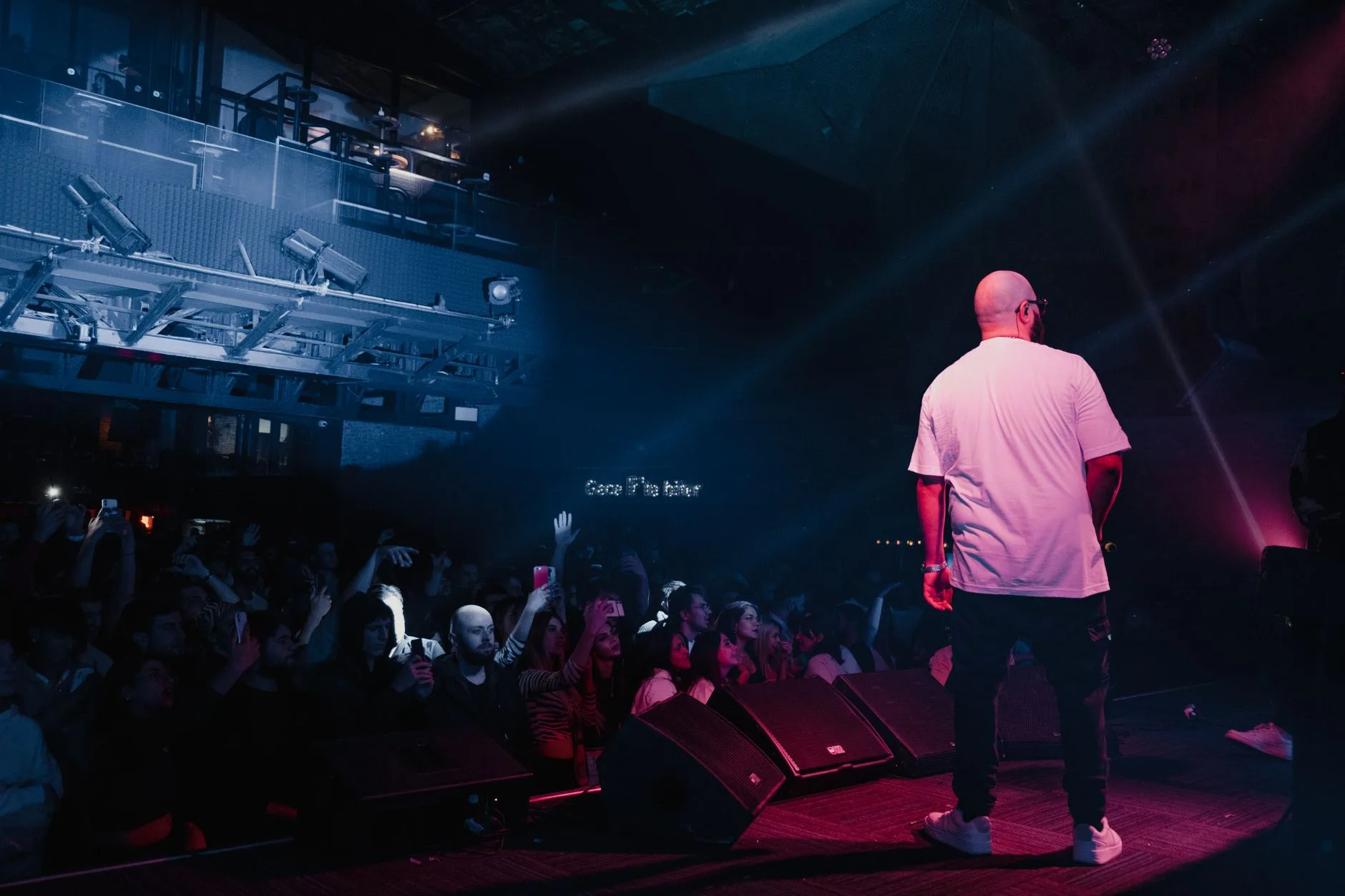 Sahne ışıkları altında performans sergileyen rap sanatçısı