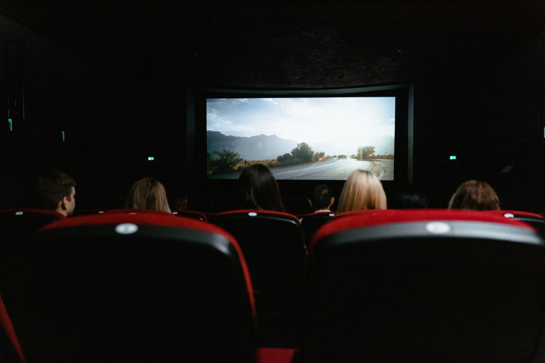 Karanlık salonda televizyon ekranına bakan sinema koltukları