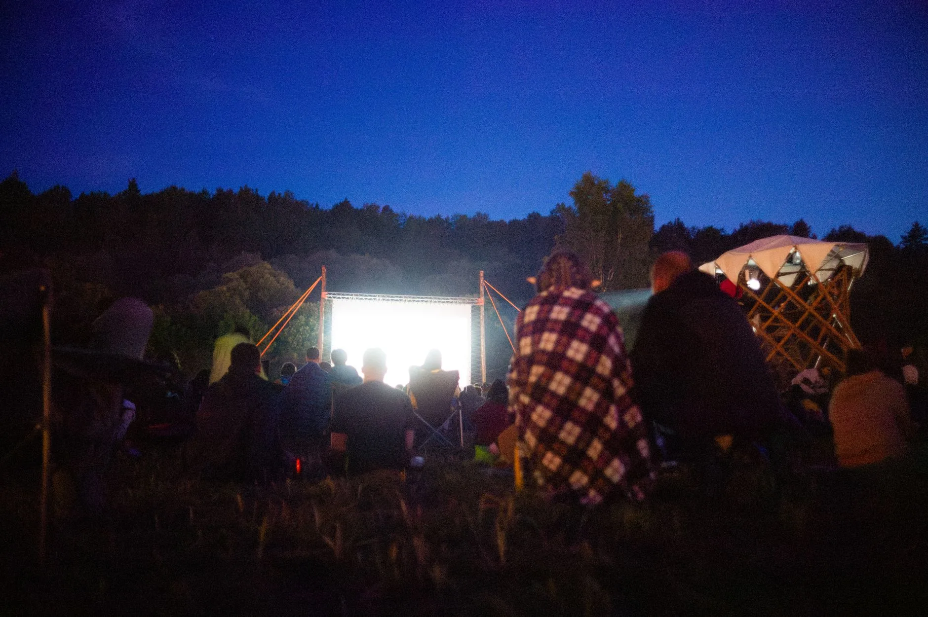 Film gösterimi sırasında projektör ışığı altında oturan izleyiciler