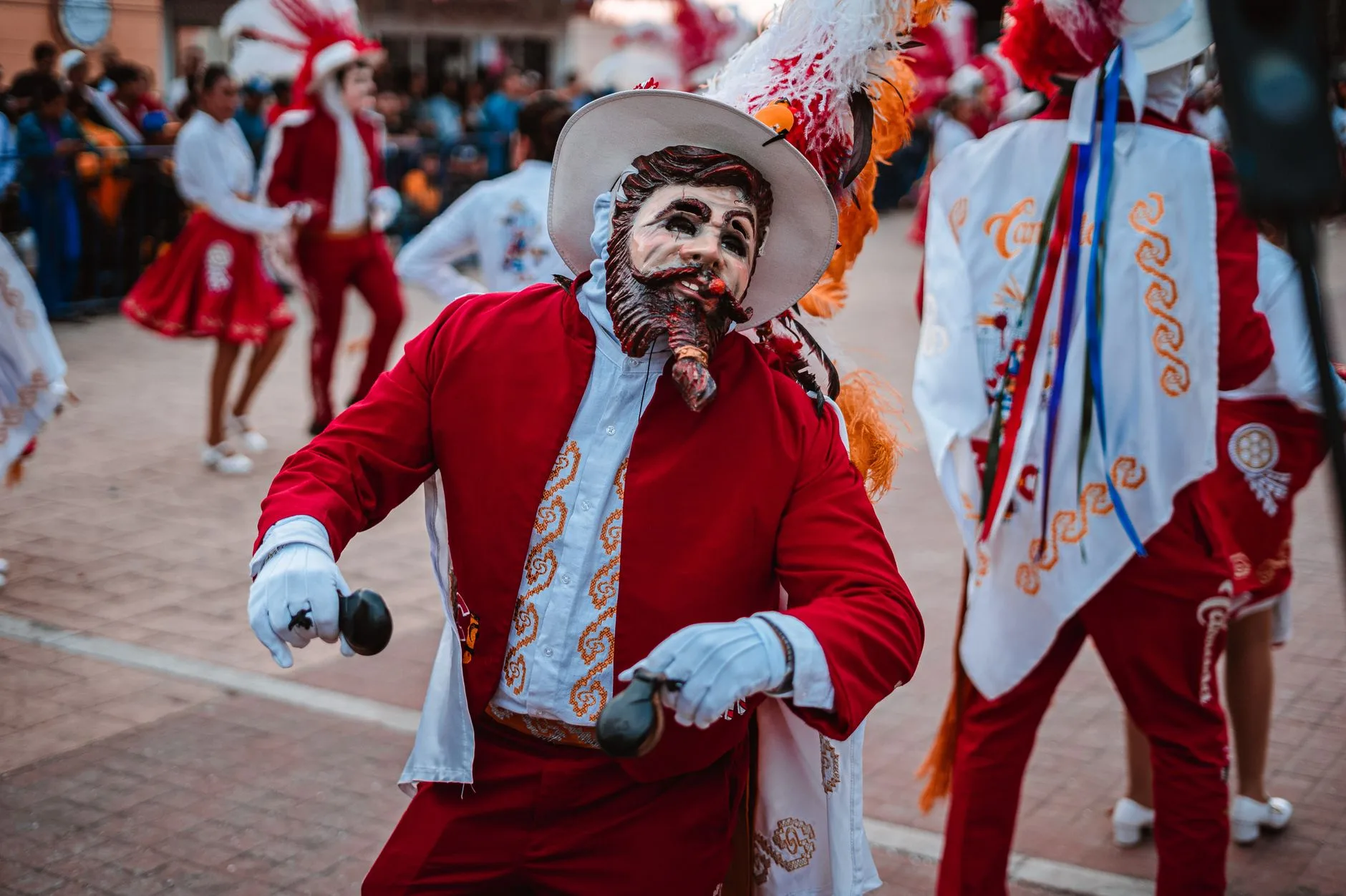 Renkli kostümlerle sokakta dans eden karnaval katılımcıları
