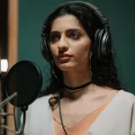 Kayıt stüdyosunda mikrofon başında müzik hazırlayan sanatçı