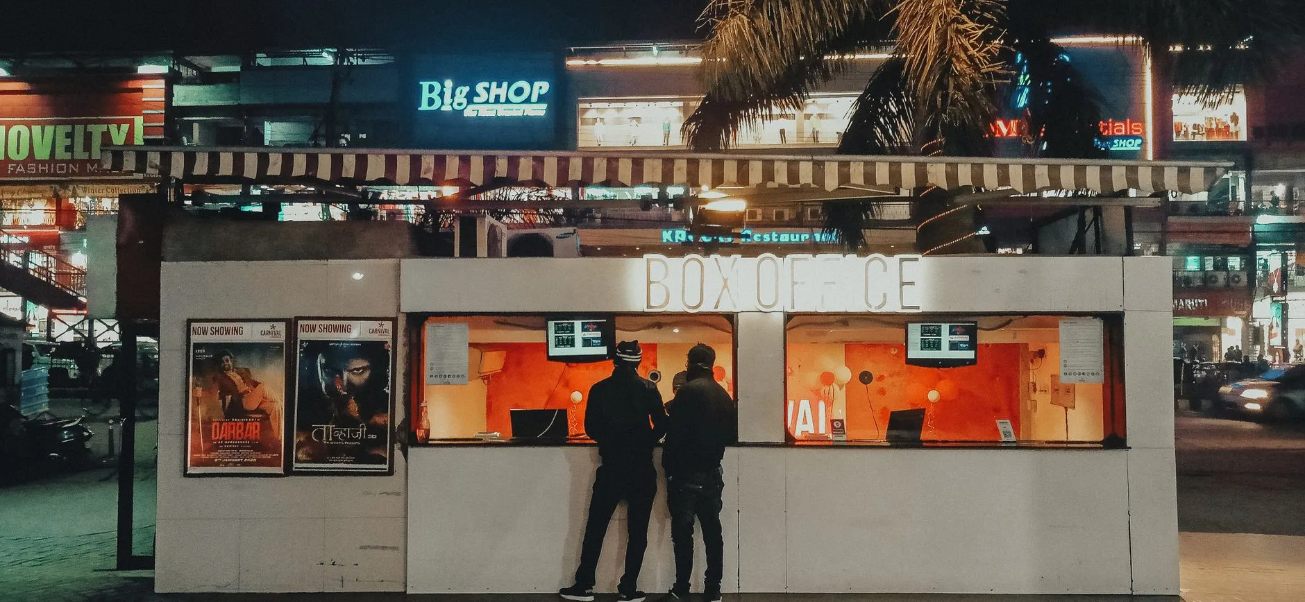 Sinema gişesinde film afişleri ve bilet kuyruğu