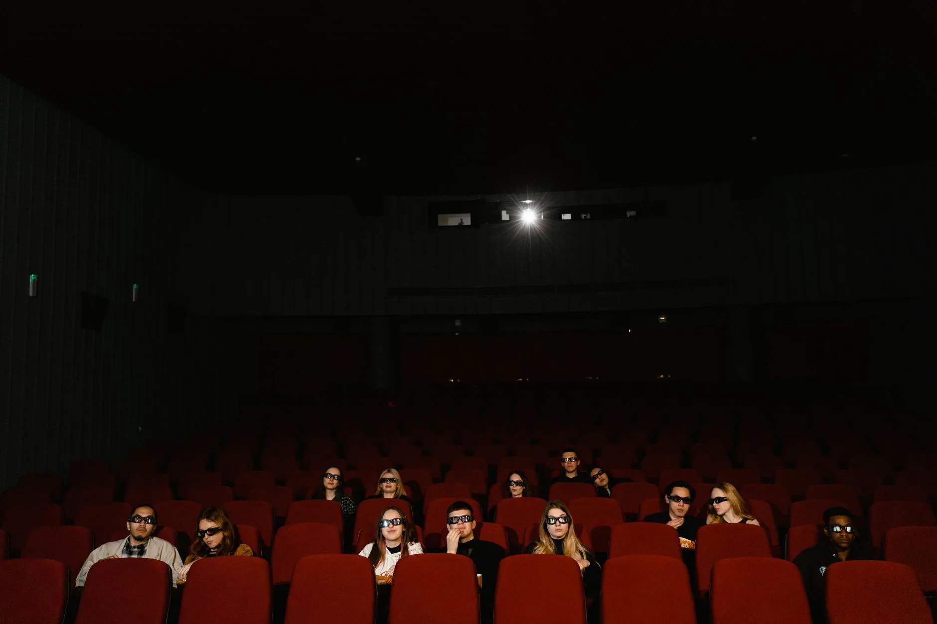 Karanlık salonda film gösterimini izleyen seyirciler