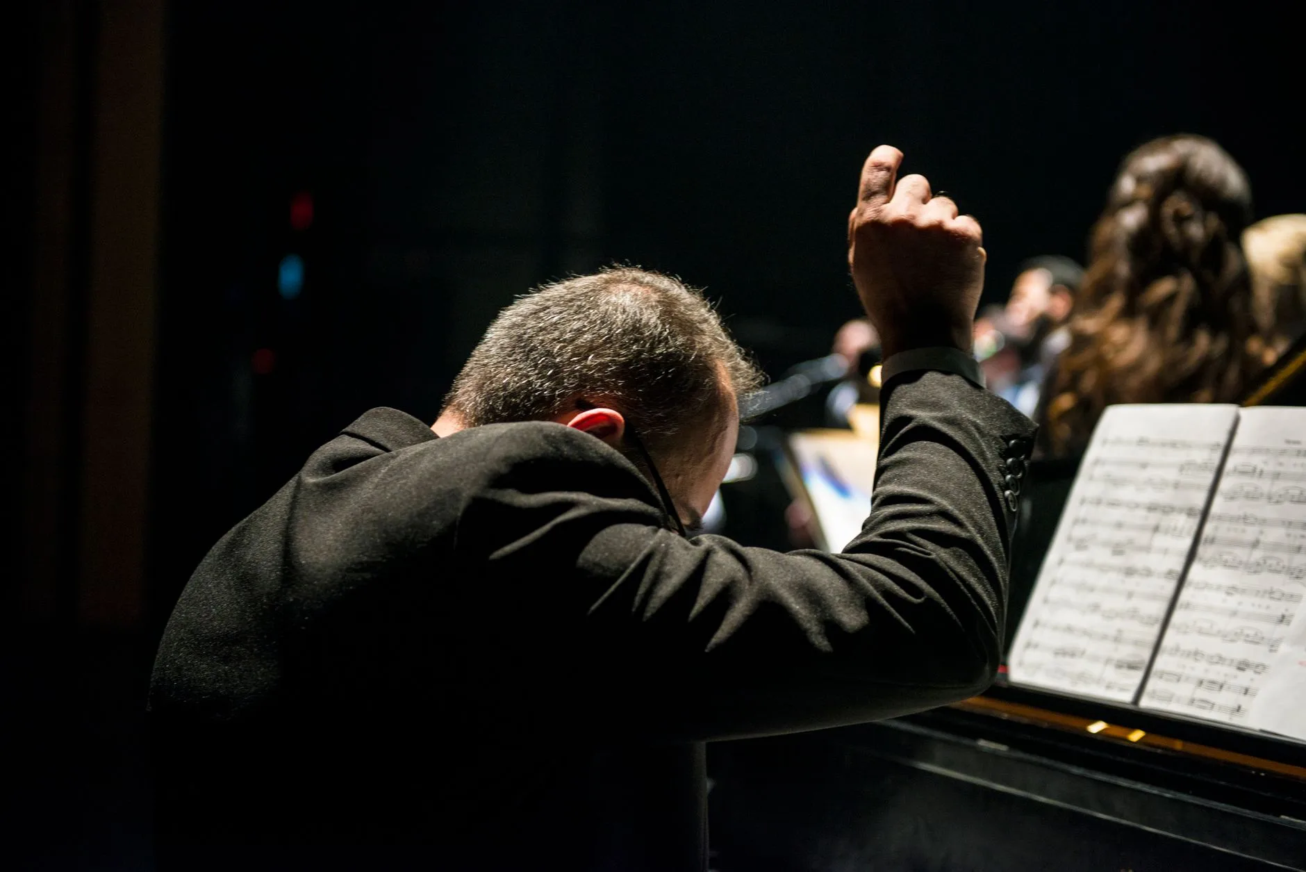 Dramatik ışıklar altında orkestra yöneten şef