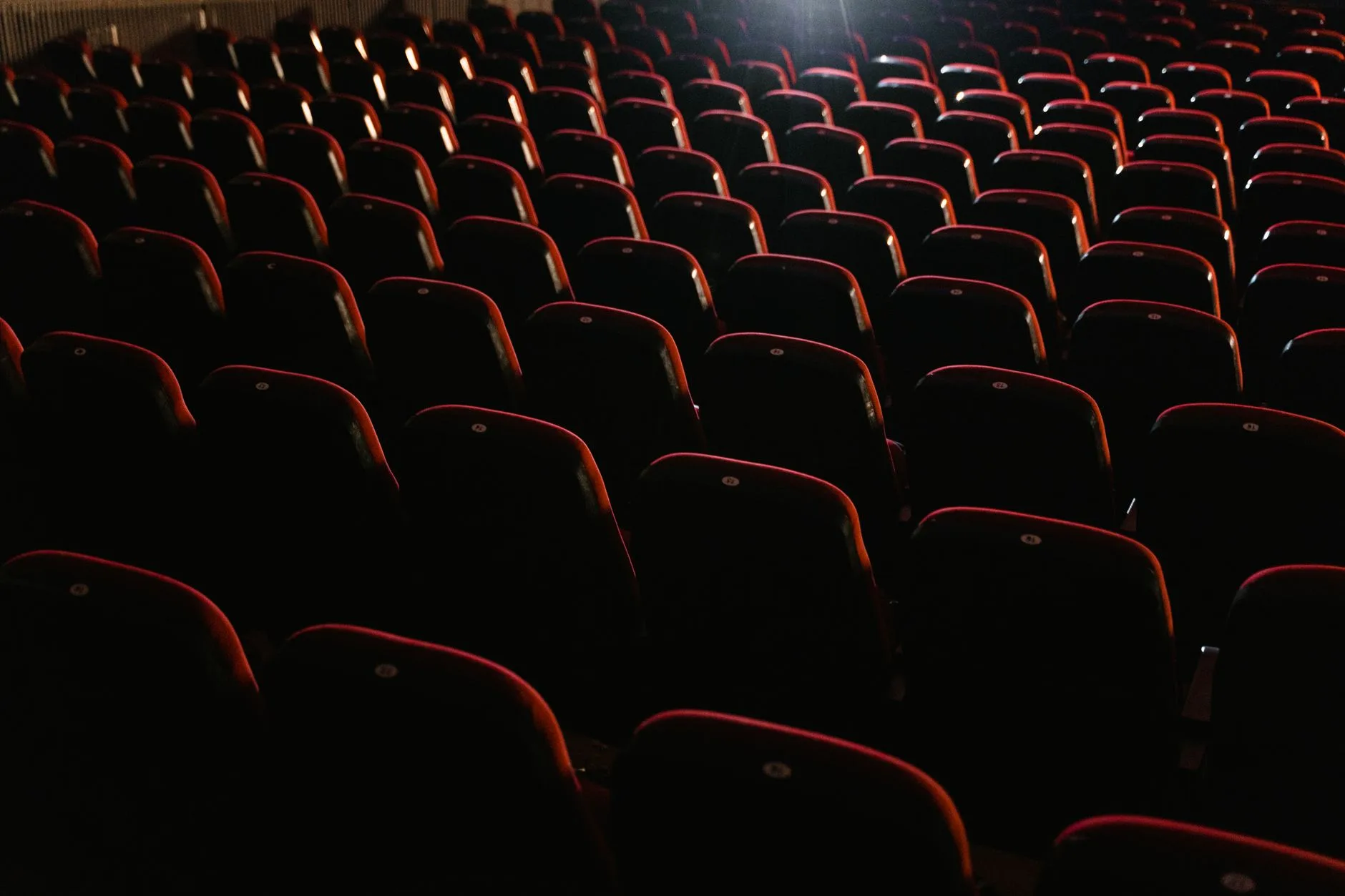 Loş ışıklarla aydınlatılmış boş sinema koltukları