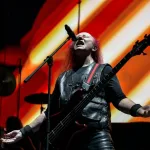 Karanlık sahnede performans sergileyen heavy metal müzisyenleri
